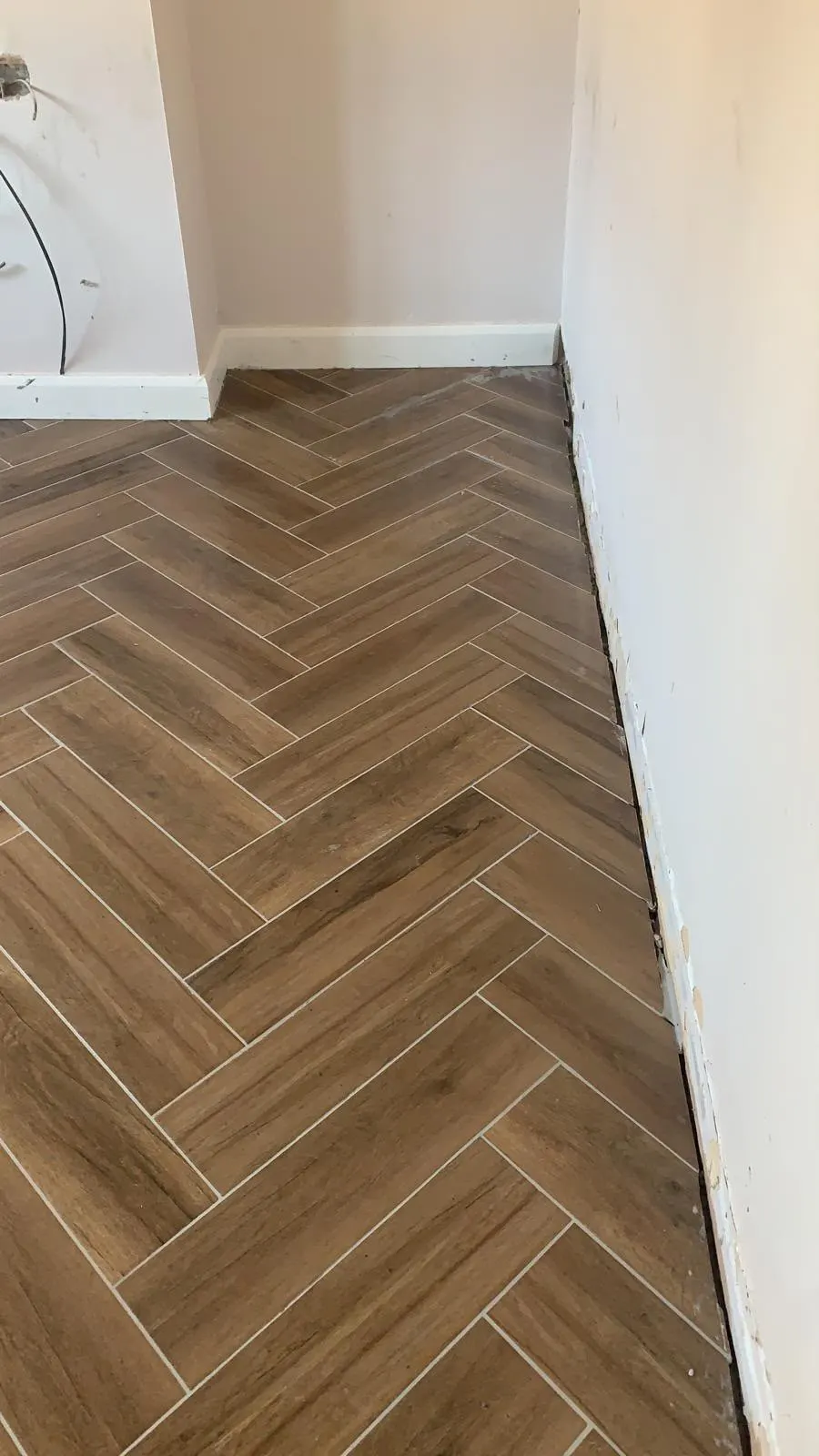 Floor and wall tiling in London: wood-effect herringbone tiles in a renovated room