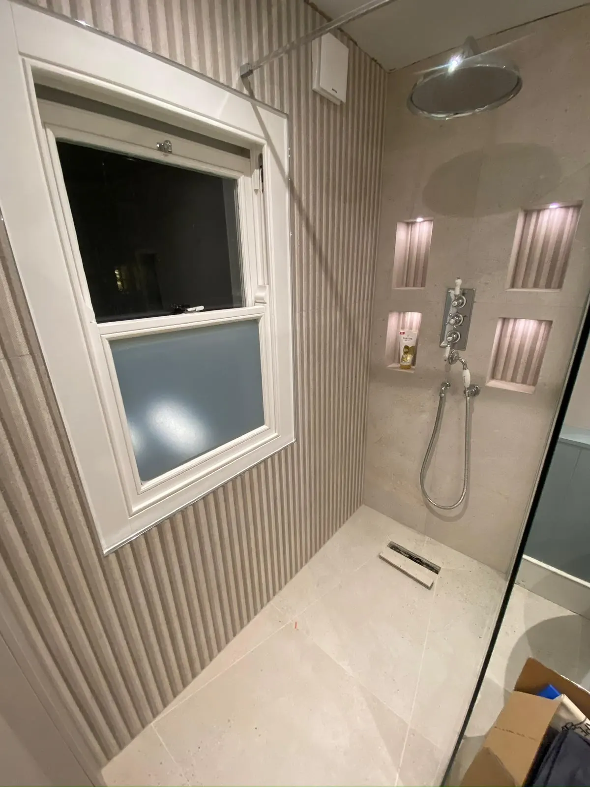 Bathroom renovation in London: shower with textured tiles and illuminated recessed niches