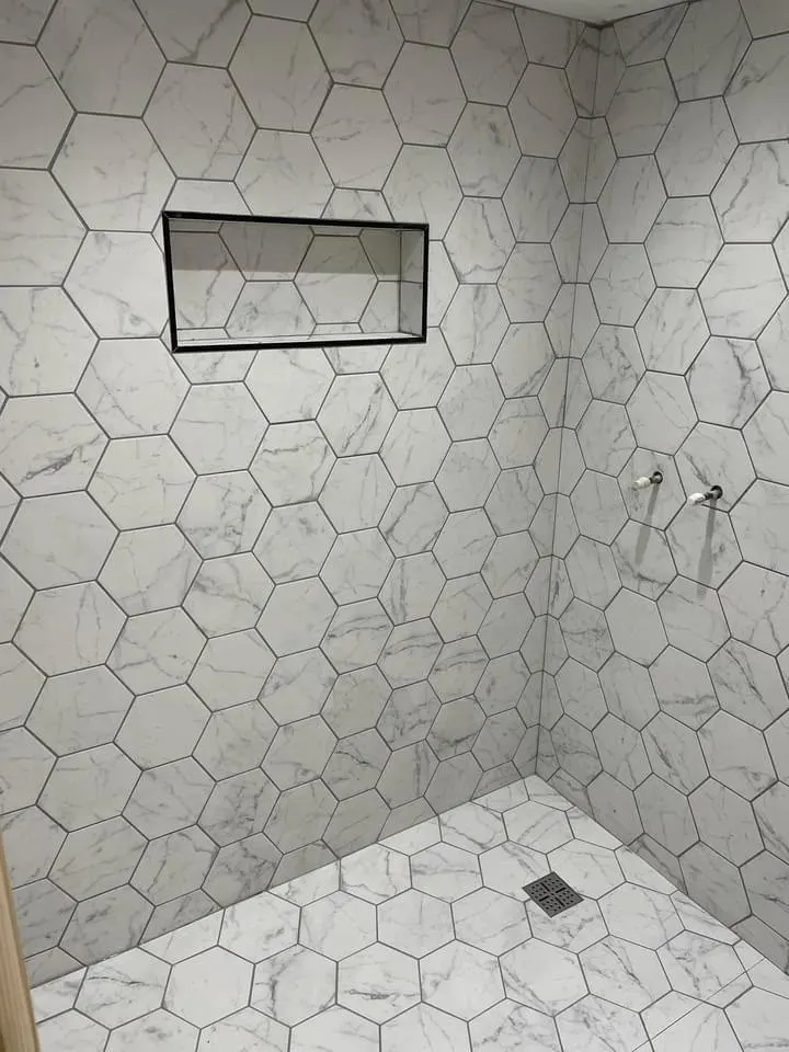 Bathroom renovation in London: hexagonal marble-effect wall tiles with tiled niche in progress