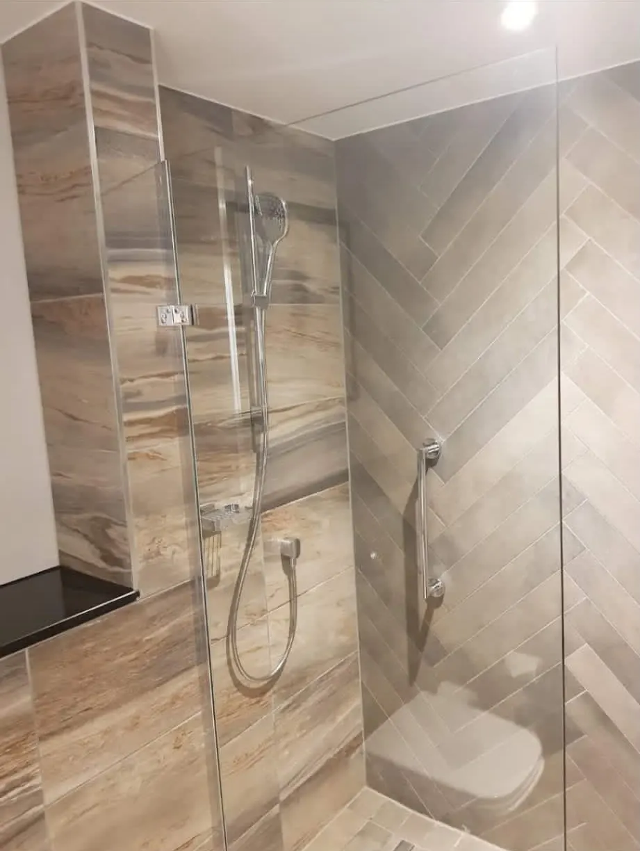 Bathroom renovation in London: shower enclosure with warm stone-effect diagonal tiling