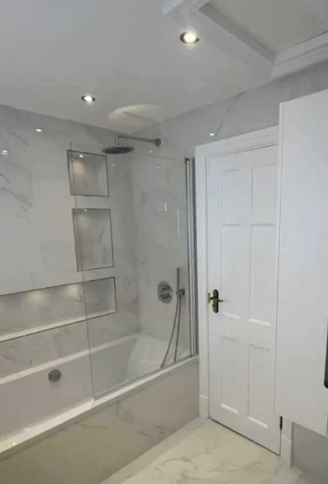 Bathroom renovation in London: pale marble-effect bath and shower with glass screen