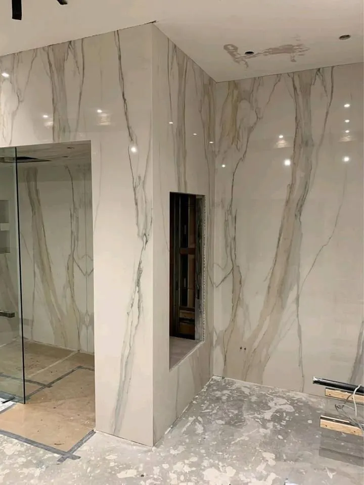 Bathroom renovation in London: marble-effect wall tiling before shower floor is finished