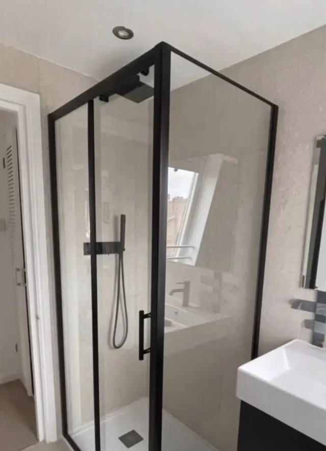 Bathroom renovation in London: black-framed shower enclosure beside white basin