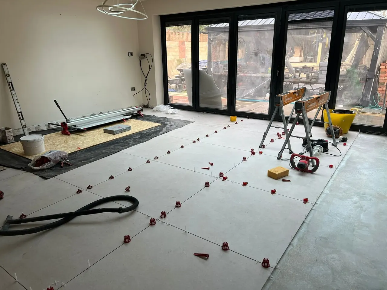Floor and wall tiling in London: large-format porcelain floor tiles being laid with levelling clips