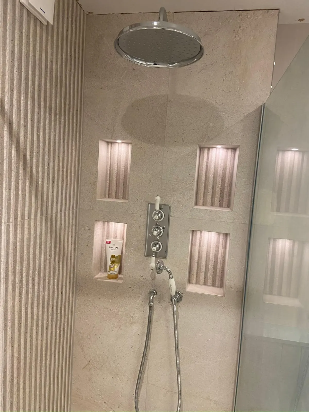Bathroom renovation in London: beige shower wall with rain shower and recessed niches
