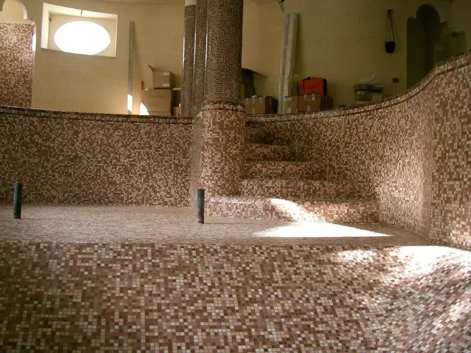 Floor and wall tiling in London: mosaic-tiled pool with tiled steps and columns
