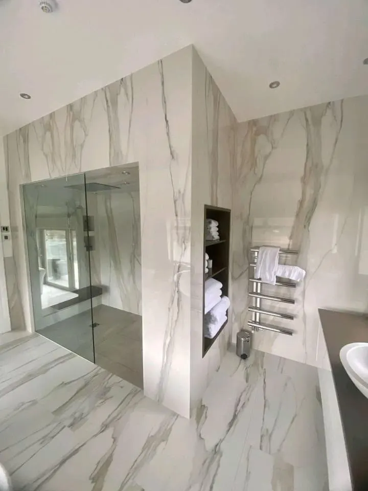 Bathroom renovation in London: glass shower enclosure with recessed towel storage and heated towel rail