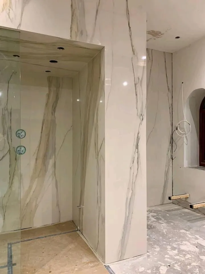 Bathroom renovation in London: marble-effect walls and shower enclosure in progress