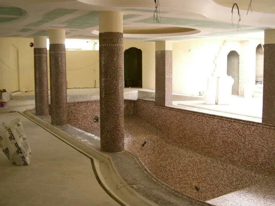 Floor and wall tiling in London: indoor pool with mosaic-tiled columns and walls