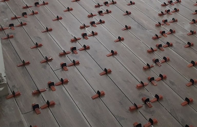 Wooden flooring in London: wood-effect planks being levelled during installation