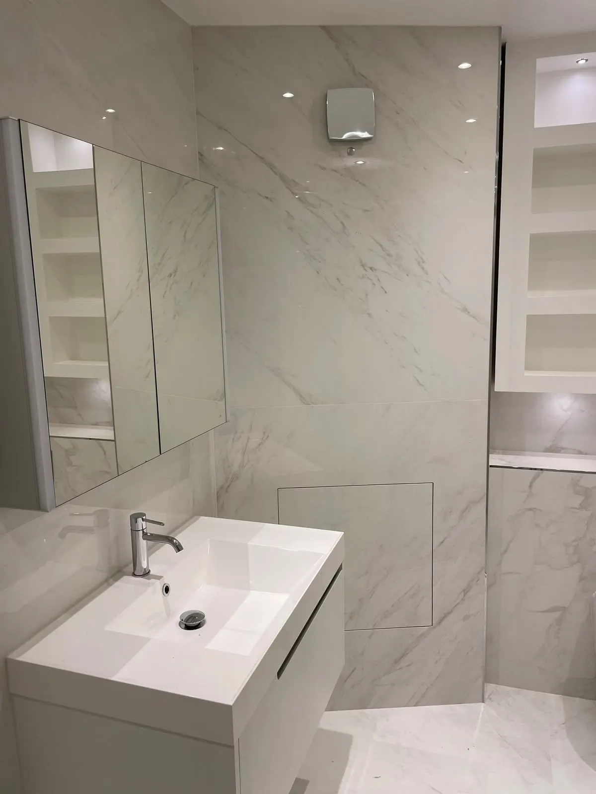 Bathroom renovation in London: marble-effect vanity, mirrored cabinet and built-in shelves