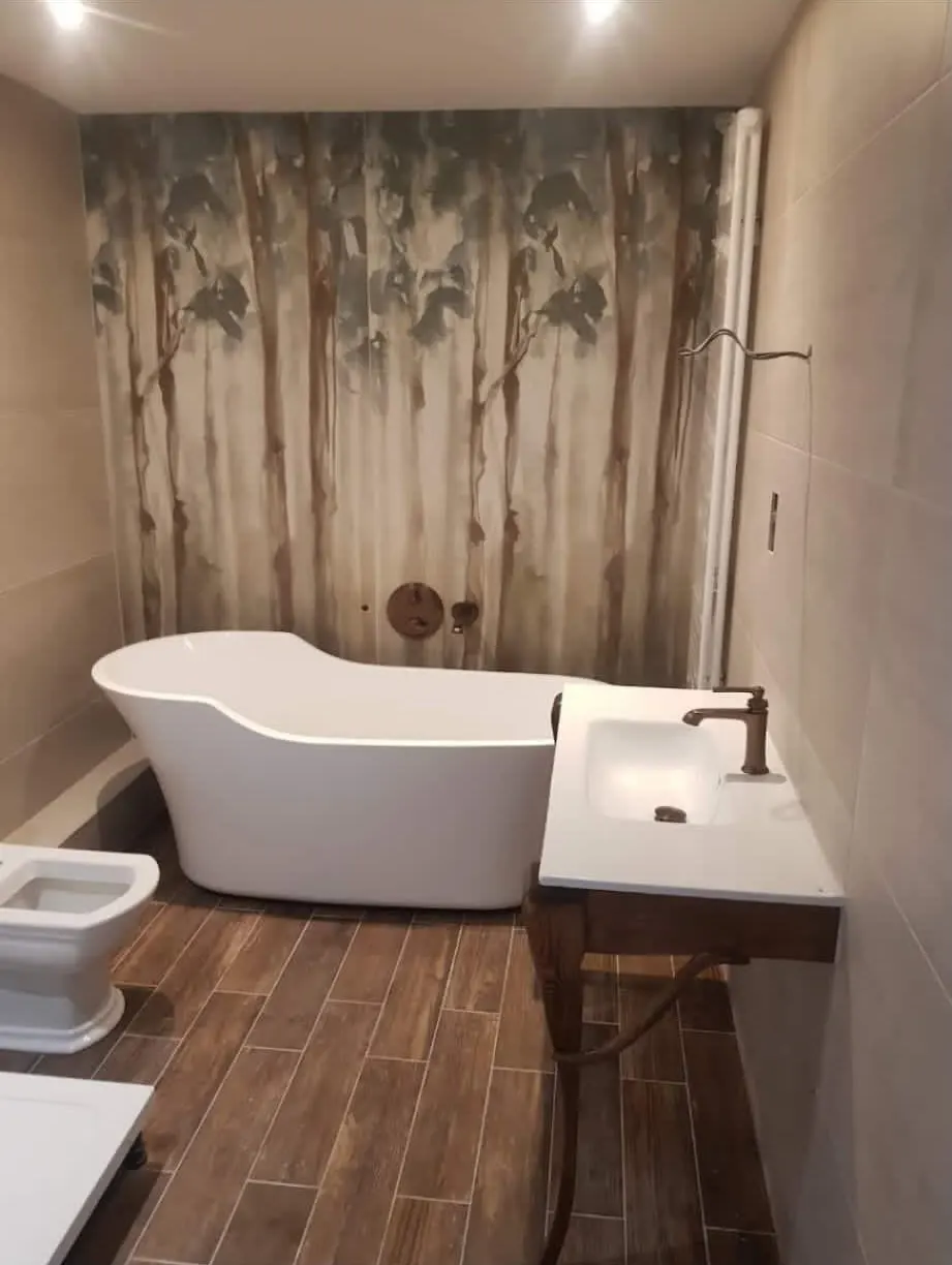 Bathroom renovation in London: freestanding bath with wood-effect floor tiles and feature wall