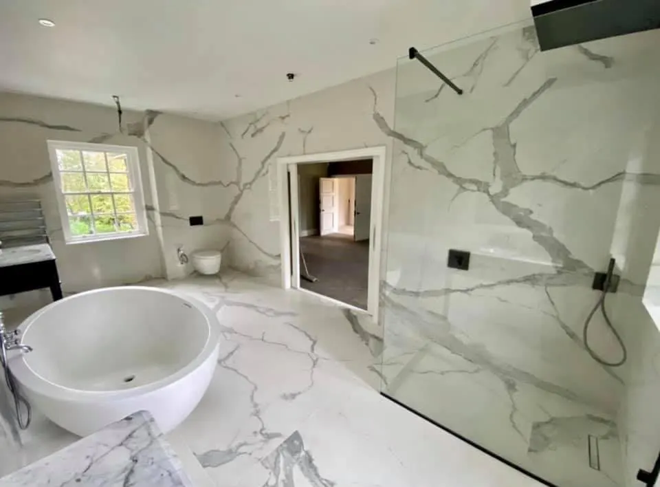 Bathroom renovation in London: freestanding bath and shower enclosure in veined marble-effect tiles