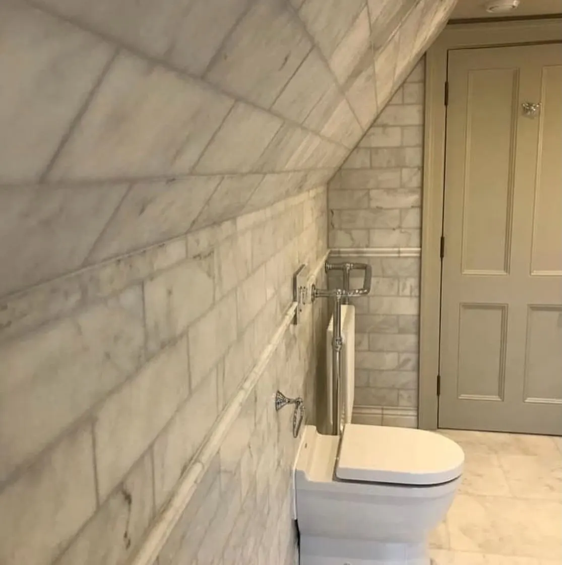 Marble and stone installation in London: marble metro tiles on a sloped loft bathroom ceiling