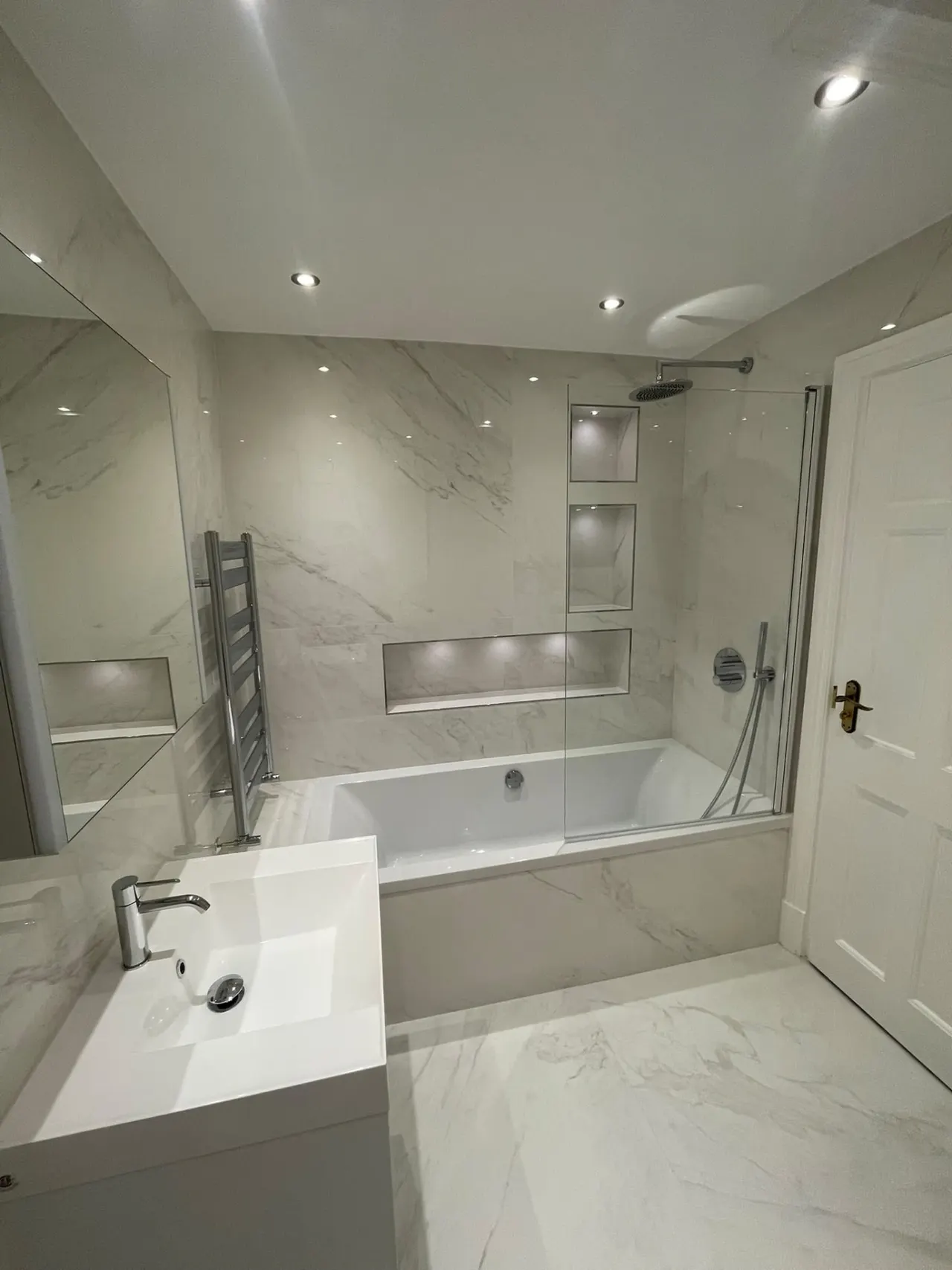 Bathroom renovation in London: large marble-effect bathroom with bath, shower and niches