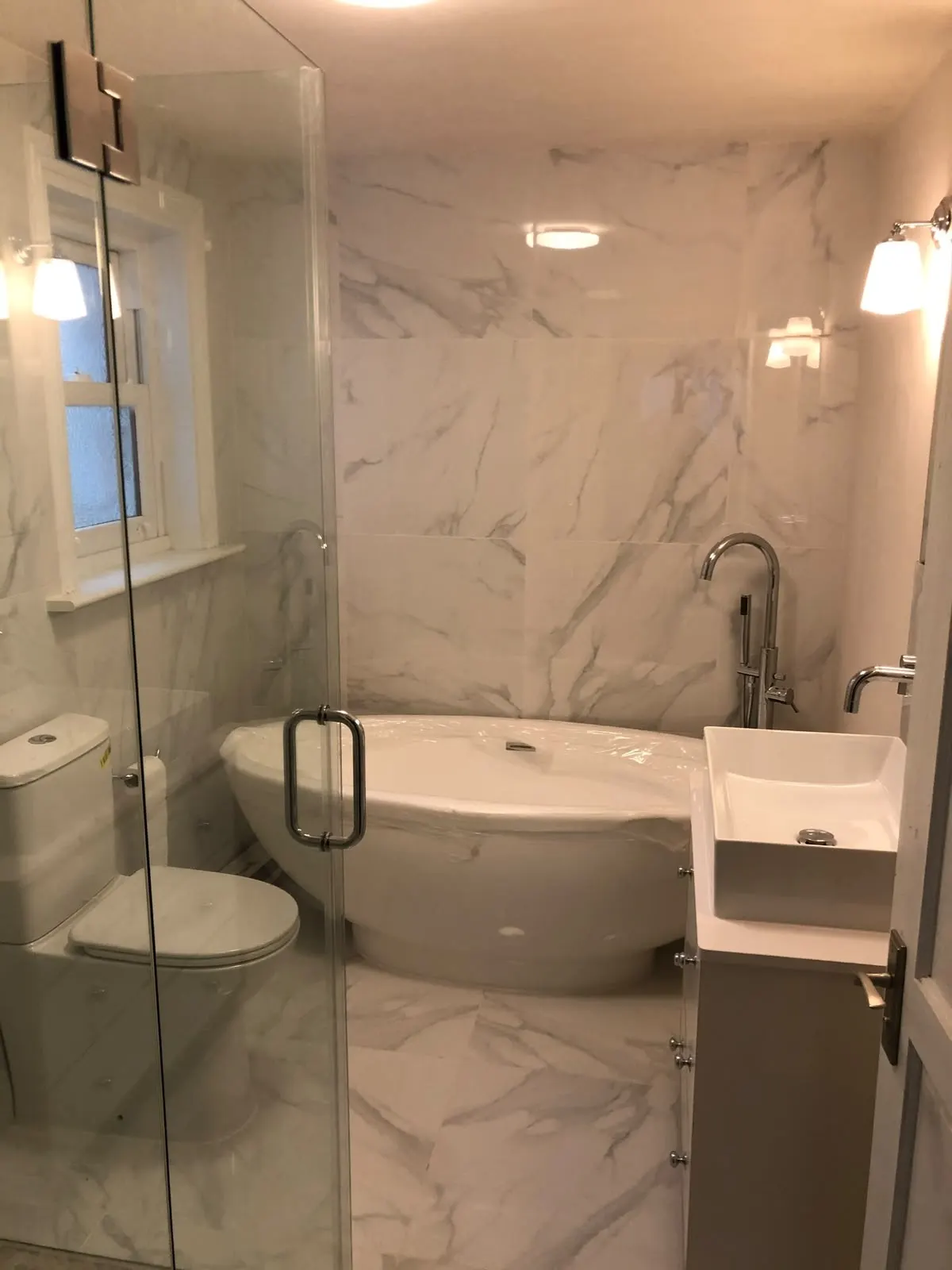 Bathroom renovation in London: compact bathroom with bath screen, toilet and basin