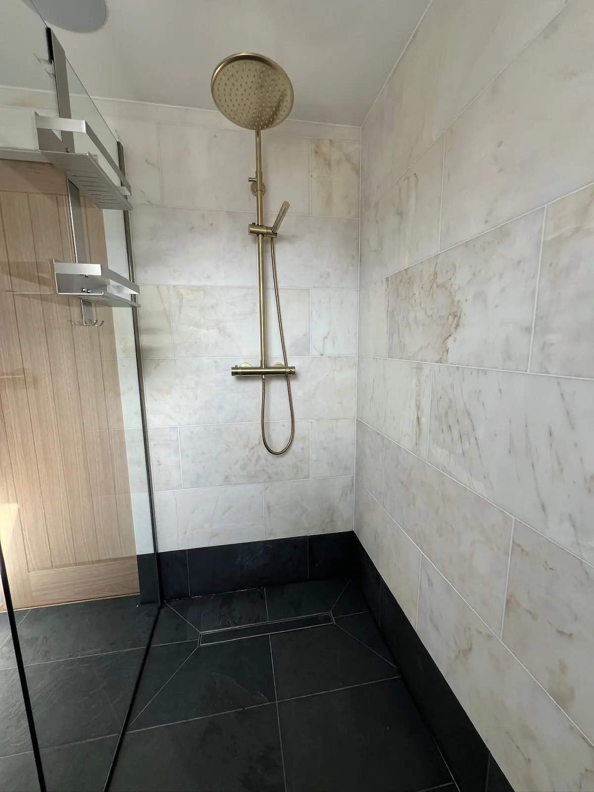 Bathroom renovation in London: walk-in shower with stone-effect tiles and brass fittings