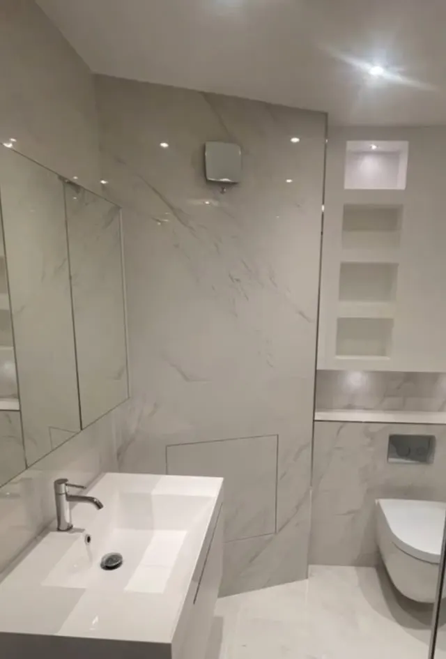 Bathroom renovation in London: white marble-effect vanity, mirror and recessed shelving