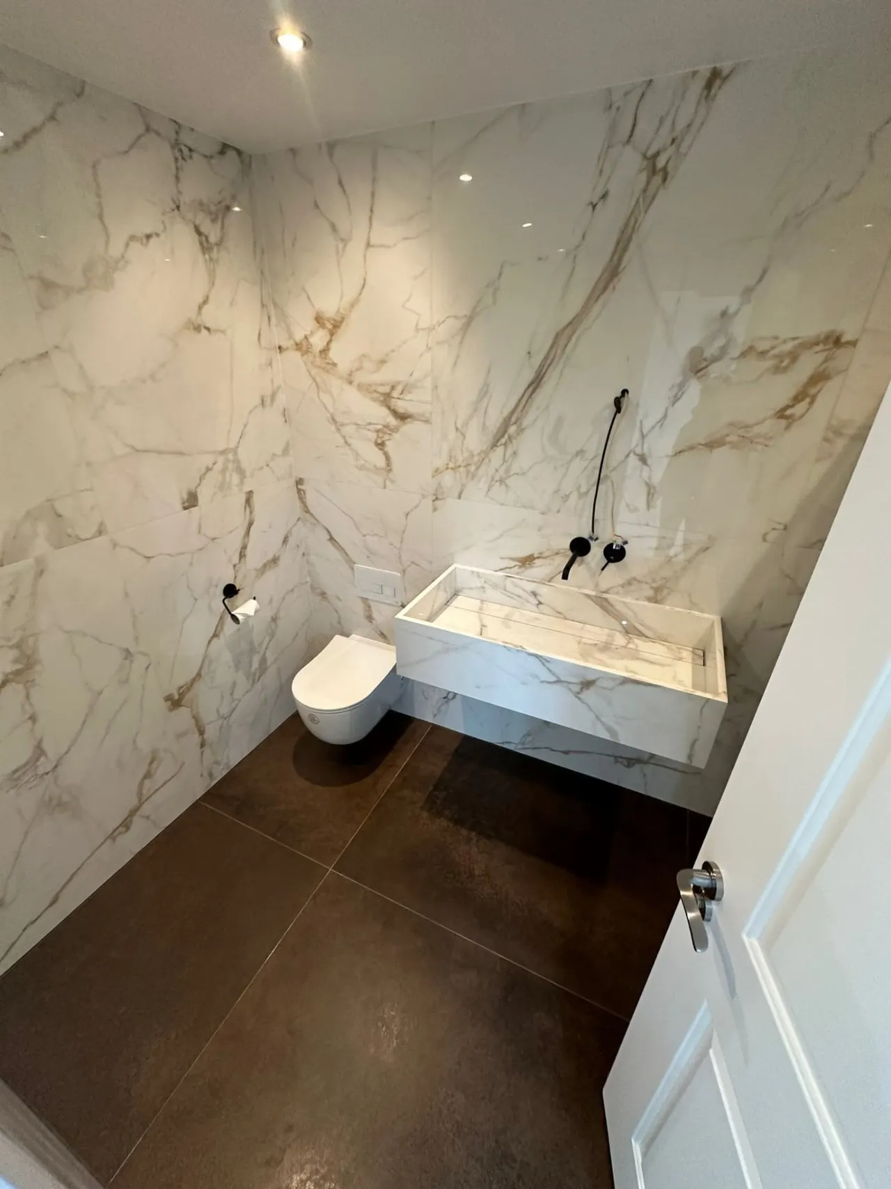 Bathroom renovation in London: small bathroom with marble-effect walls and floating basin