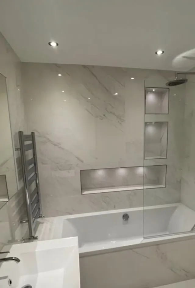 Bathroom renovation in London: marble-effect bath and shower with recessed niches